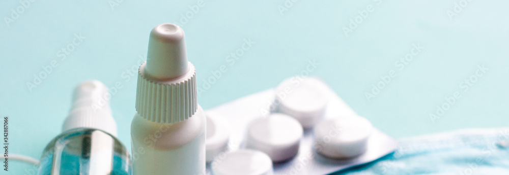 Fototapeta premium Pills, tablets and bottle on turquoise background. Copy space