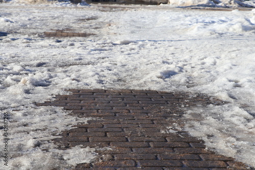 Snow and concrete plates  on the pedestrian path. Thaw after winter in the city.
