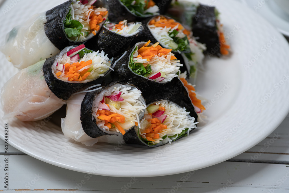 Vietnamese vegan rice paper and nori sheet spring rolls on white plate Vietnamese vegan rice paper and nori sheet spring rolls on white plate