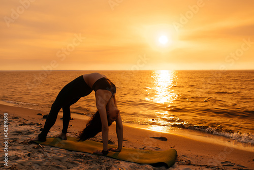 A girl practices yoga by the sea during a beautiful sunset. Fitness and healthy lifestyle