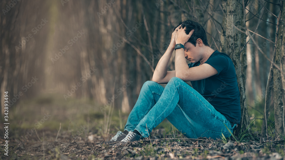 Unhappy man in the forest suffers from depression and frustration of life. copy space Unhappy man in the forest suffers from depression and frustration of life. copy space