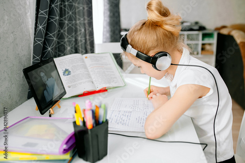 Quadro em tela Teen girl school pupil wears headphones conference calling studying online with remote tutor from home