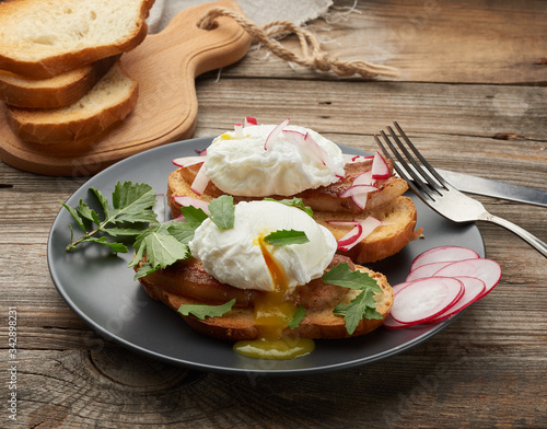sandwich on toasted white slice of bread with poached eggs, green leaves of arugula and radish