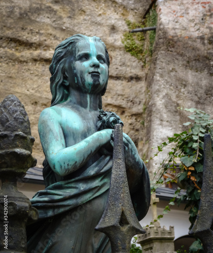 Old bronze statue of young girl at St Peters cemetery in Salzburg Austria