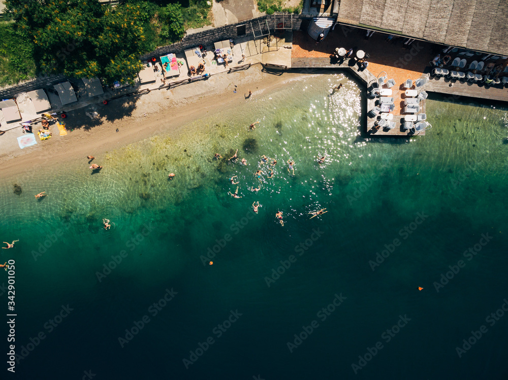 Aerial view of people swimming in the sea. Beach cafe by the sea. People bathe in the Bay of Kotor, in the town of Perast, in Montenegro