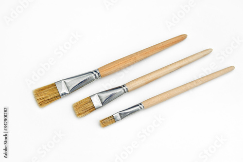 three art brushes made of natural bristles of different sizes on a white background