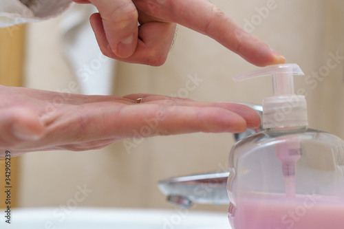 Close-up of man washing hands with soap under bathroom sink.