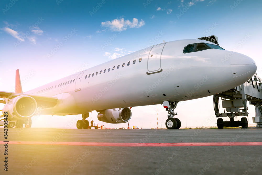 A white passenger aircraft at the boarding bridge in the rays of the evening sun A white passenger aircraft at the boarding bridge in the rays of the evening sun