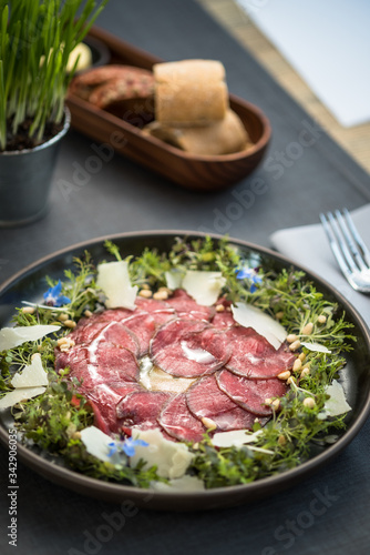 Carpaccio thin sliced beef meat with cheese, herbs