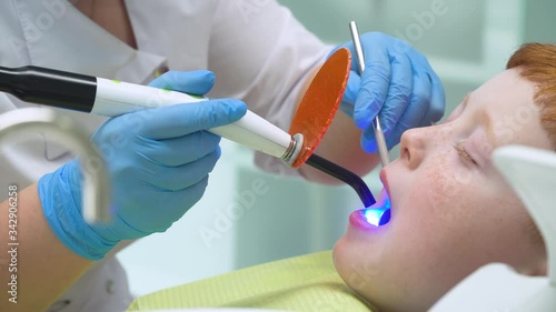 Female dentist in work. Little boy at reception at dentist in dental chair. Pediatric dentistry photo