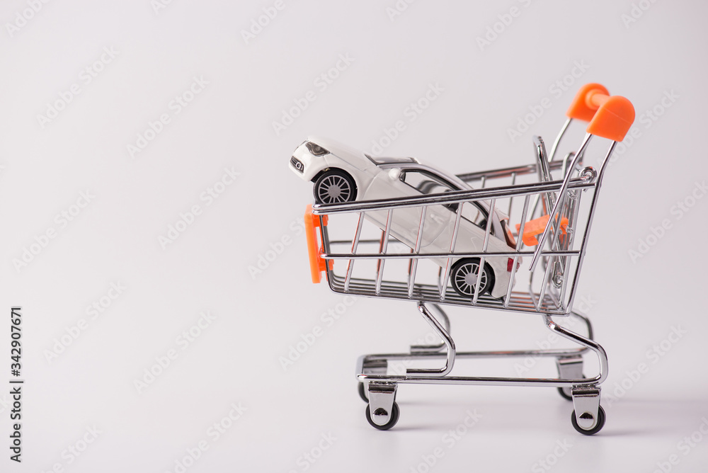 Buy new white car parking tax industry concept. Side profile close up photo of small mini toy car lying in shopping cart isolated over grey background with empty blank space