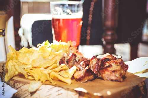 Roasted meat with potato chips on a wooden stand with a glass of red fruit drink
