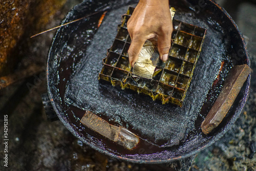 Surakarta Indonesia, December 5, 2020: Closeup hand to make batik with a stamp to the hot night candles with bokeh background
 photo