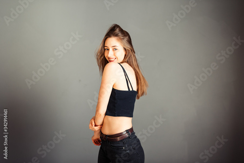 Portrait of a girl in a black top with her hair against a gray background. Without makeup, without retouching.