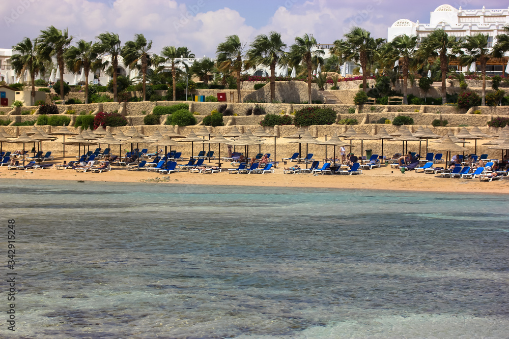 Luxury resort: coast and straw umbrellas for protection from the sun, lazy summer holiday by the sea, sunny beautiful day.