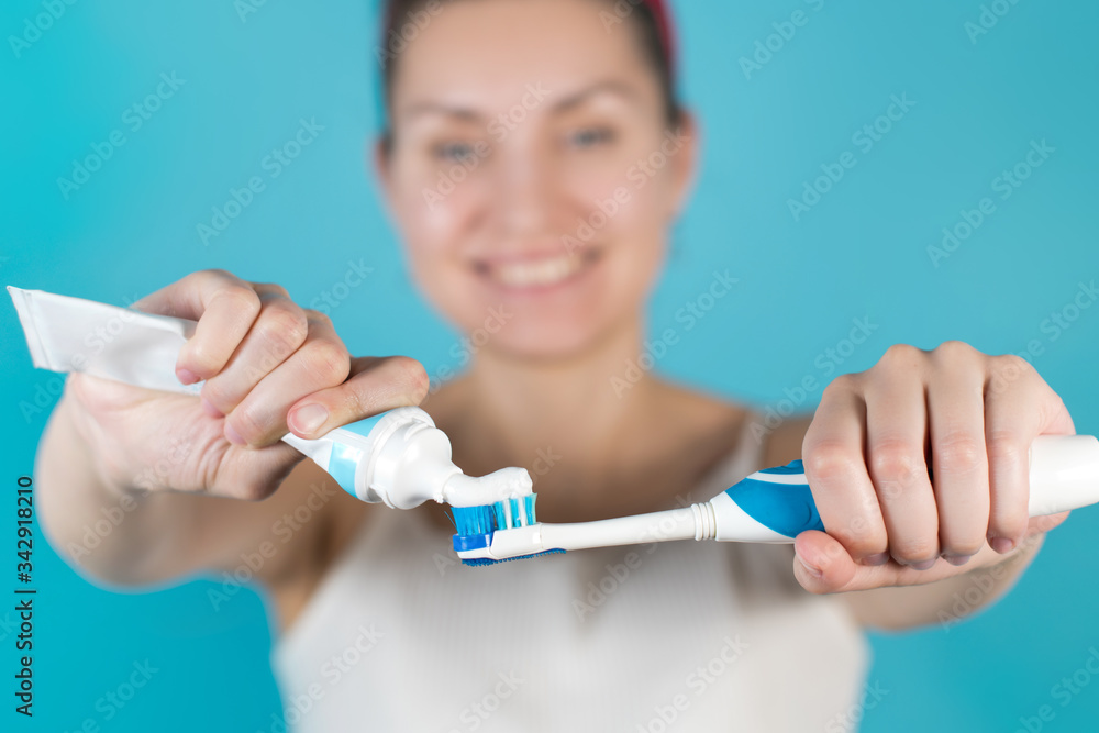 Close-up of a toothbrush and paste in the hands of a girl on a blue background Close-up of a toothbrush and paste in the hands of a girl on a blue background