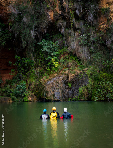 grupo de hombres aventureros espeleólogos metidos en el agua mirando el descenso del barranco