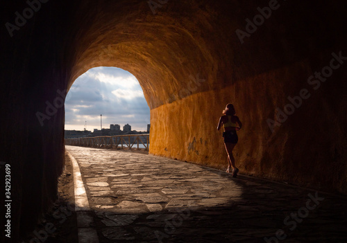 Mujer atravesando un túnel de tren corriendo hacia la luz