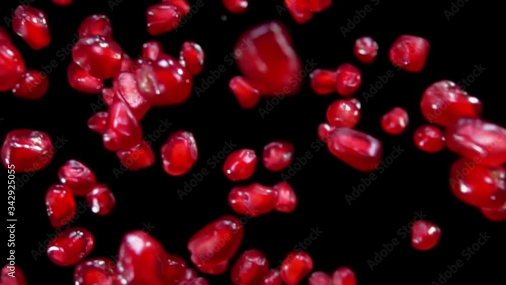 Juicy red grains of ripe pomegranate are flying diagonally on a black background in slow motion, loop footage Juicy red grains of ripe pomegranate are flying diagonally on a black background in slow motion, loop footage