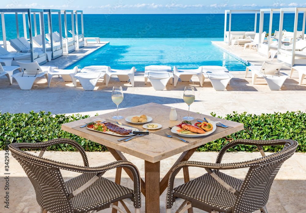 Oceanfront restaurant table, pool and ocean background, food and drinks, bread and butter