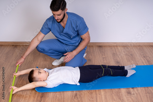 Physiotherapist with young boy. Exercising on the mat. Physiotherapist and his pathient in the clinic photo