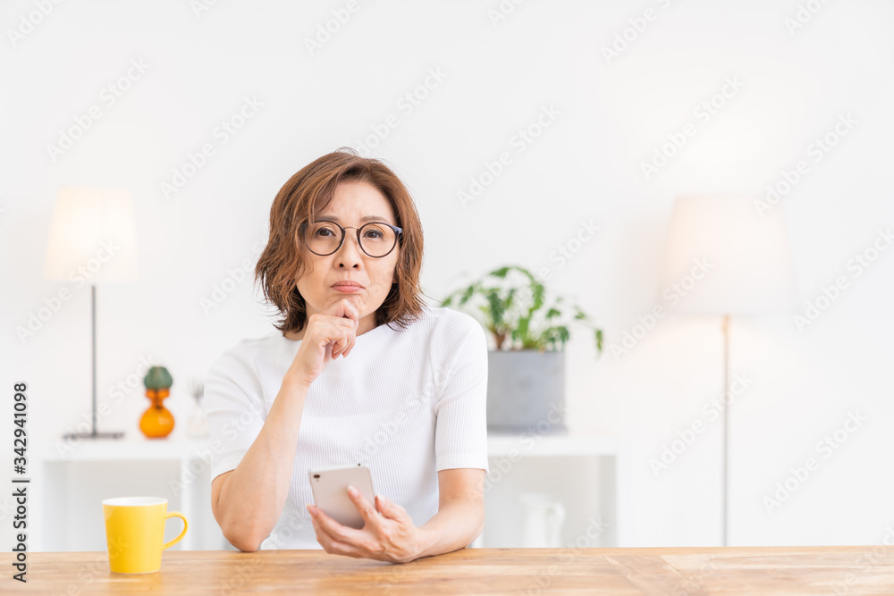 スマートフォンを見るシニア女性 考える スマートフォンを見るシニア女性 考える