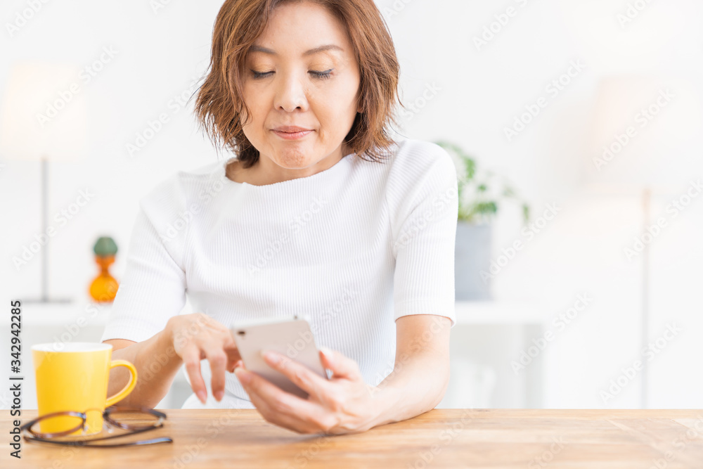 部屋でスマホを見るシニア女性 部屋でスマホを見るシニア女性