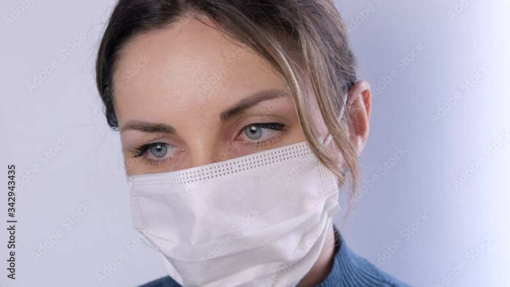 Portrait Beautiful young woman with tousled hair tired eyes in medical mask on a white background close-up view. Nurses, medical staff during epidemic. Health care Coronavirus and medical concept Portrait Beautiful young woman with tousled hair tired eyes in medical mask on a white background close-up view. Nurses, medical staff during epidemic. Health care Coronavirus and medical concept