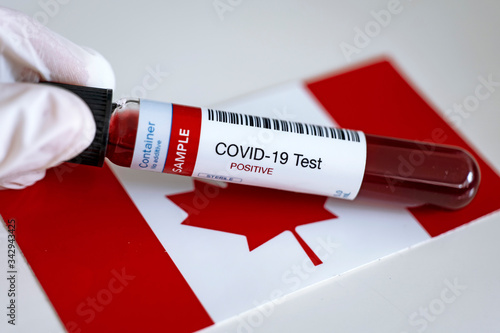 Testing for presence of coronavirus in Canada. Tube containing a blood sample that has tested positive for COVID-19. Canadian flag in the background. photo