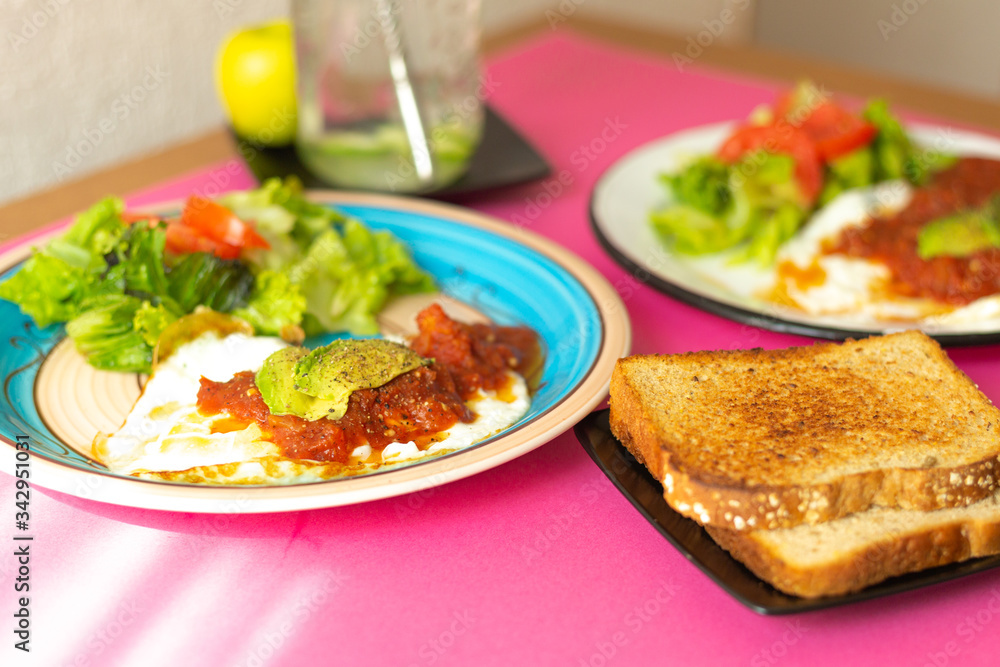 Huevos, recién horneados con una salsa de tomate y una ensalada con aguacate, para una dieta keto o personas fit. Huevos, recién horneados con una salsa de tomate y una ensalada con aguacate, para una dieta keto o personas fit.