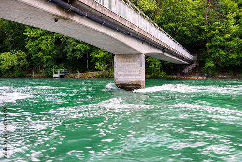 Concrete bridge over the river in a beautiful turquoise color, visible forest along the river. © Michal