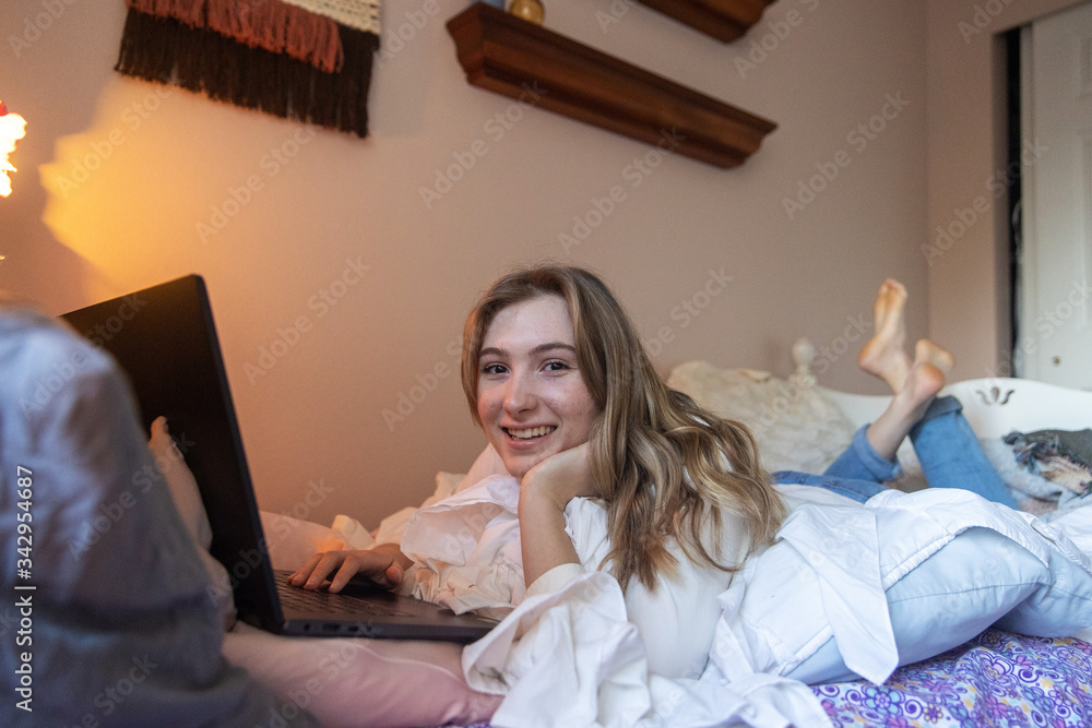 Young woman laying down looking at laptop computer while working at home Young woman laying down looking at laptop computer while working at home