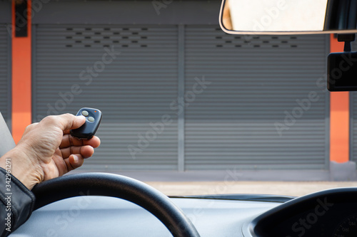 Fényképezés Man in car, hand holding and using remote control to open the automatic shutter roller steel garage
