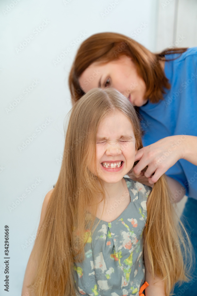 mom makes ponytails of her little daughter mom makes ponytails of her little daughter