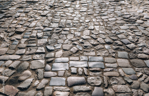The dark gray paving stones laid out in a semicircle. The texture of the old dark stone. Road surface. Vintage, grunge.