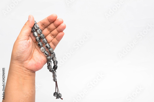 Hand holding muslim beads rosary or tasbih isolated on white background.