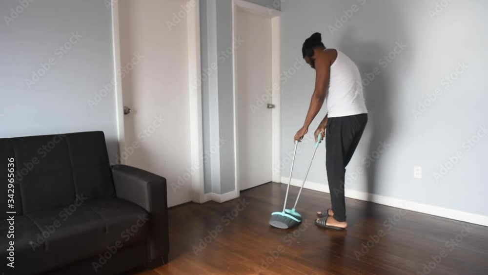 Cool black man cleaning the house with broom. African american man on quarantine use broom to swep his flat. Funny concept Cool black man cleaning the house with broom. African american man on quarantine use broom to swep his flat. Funny concept