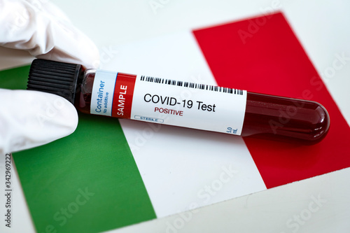 Testing for presence of coronavirus. Tube containing a blood sample that has tested positive for COVID-19. Flag of Italy in the background. photo