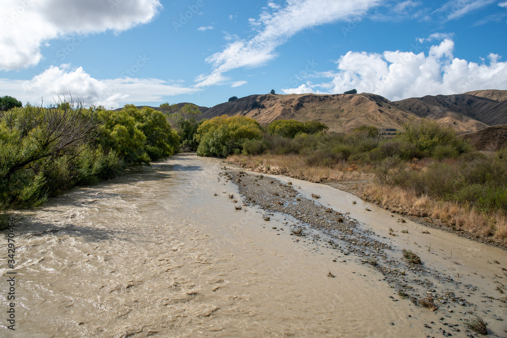 Flooded river with fast flowing dirty silty water after heavy rain Flooded river with fast flowing dirty silty water after heavy rain