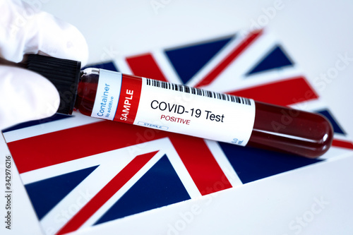 Testing for presence of coronavirus. Tube containing a blood sample that has tested positive for COVID-19. Flag of the United Kingdom in the background. photo