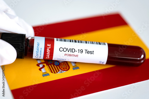 Testing for presence of coronavirus in Spain. Tube containing a blood sample that has tested positive for COVID-19. Spanish flag in the background. photo