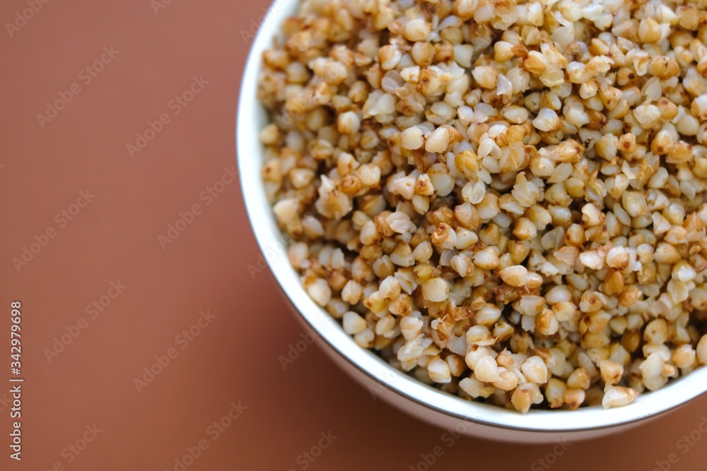 Buckwheat.Buckwheat porridge in a round plate close-up on a bright brown background.Cereals. Healthy eating. copy space. Buckwheat.Buckwheat porridge in a round plate close-up on a bright brown background.Cereals. Healthy eating. copy space.