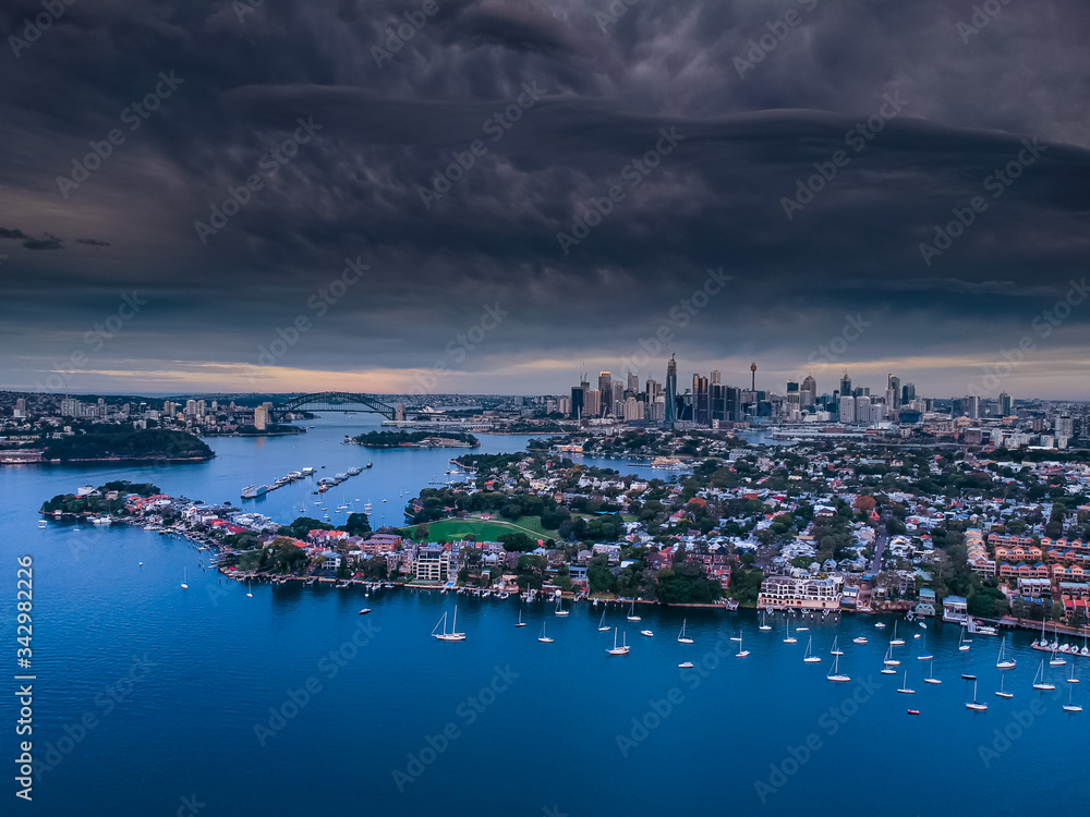 Fototapeta premium Panoramic drone aerial view over Sydney harbour on a cloudy sunset afternoon showing the nice colours of the harbour foreshore