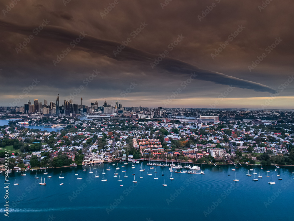 Panoramic drone aerial view over Sydney harbour on a cloudy sunset afternoon showing the nice colours of the harbour foreshore
