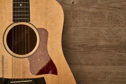 Acoustic guitar body with a red pick guard put down on a brown wooden floor