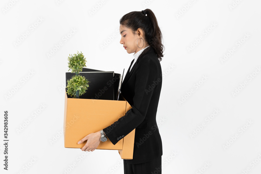 Fototapeta premium Side view of fired dismissal unemployed young Asian business woman in suit holding box with personal belongings on white isolated background. Unemployment, failure and layoff concept.