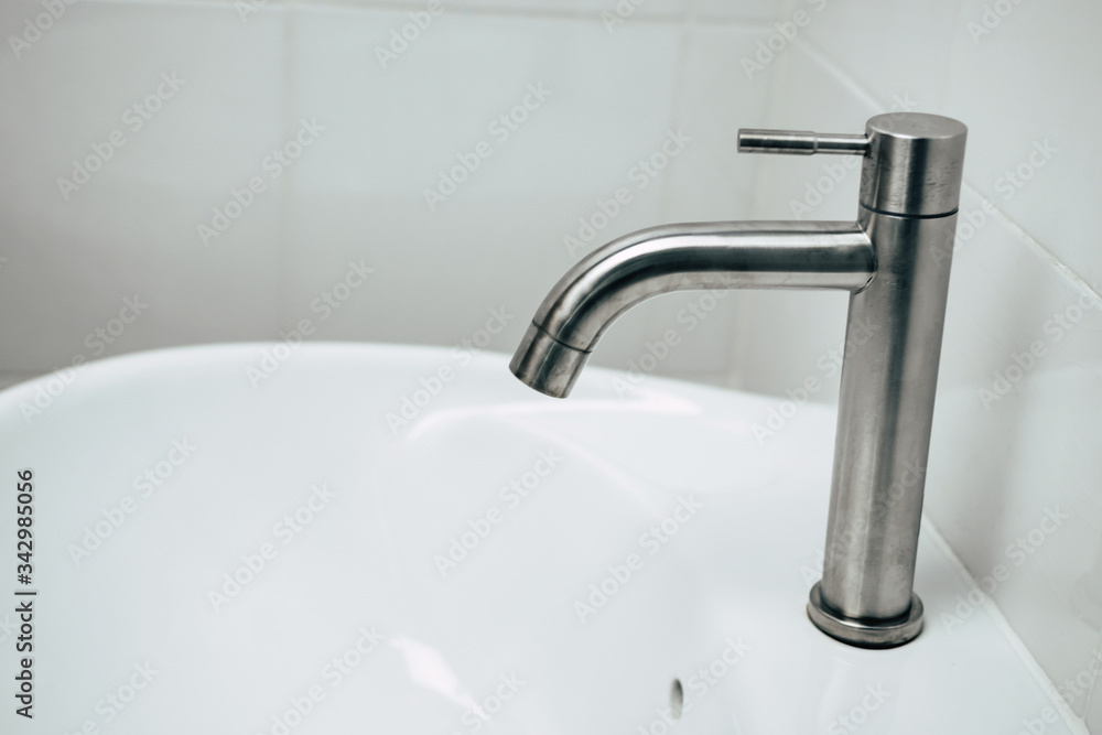 aluminium water tap with white wall background in bathroom for washing hand for claen corona virus (covid19) prevention, virus outbreak protection, cleaning hand, self quarantine and hygiene concept aluminium water tap with white wall background in bathroom for washing hand for claen corona virus (covid19) prevention, virus outbreak protection, cleaning hand, self quarantine and hygiene concept