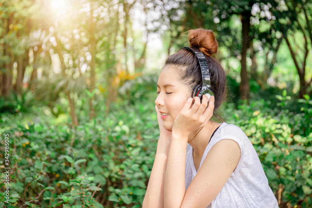 Beautiful young woman with headphones enjoying and relaxed in music in the park