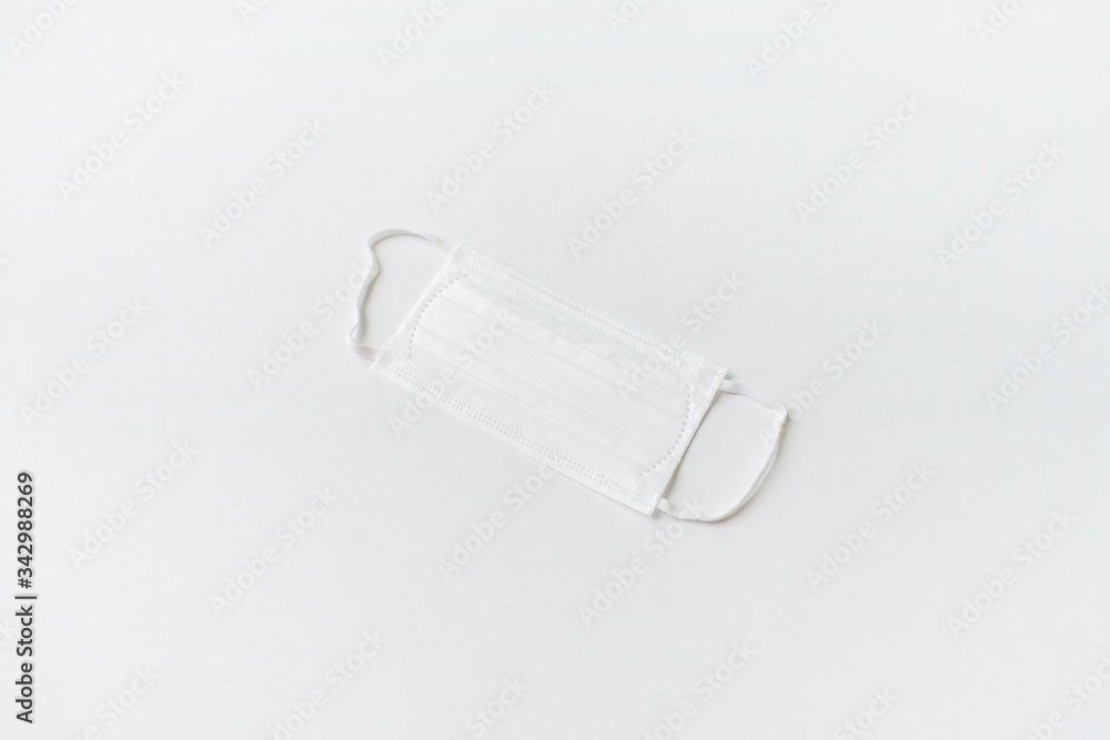 Surgical mask with rubber ear straps. Typical 3-ply surgical mask to cover the mouth and nose. Procedure mask from bacteria. Protection concept. top view. white background. Surgical mask with rubber ear straps. Typical 3-ply surgical mask to cover the mouth and nose. Procedure mask from bacteria. Protection concept. top view. white background.