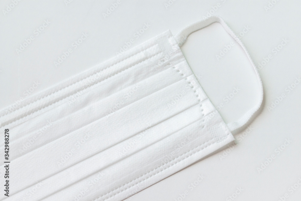 Surgical mask with rubber ear straps. Typical 3-ply surgical mask to cover the mouth and nose. Procedure mask from bacteria. Protection concept. top view. white background. Surgical mask with rubber ear straps. Typical 3-ply surgical mask to cover the mouth and nose. Procedure mask from bacteria. Protection concept. top view. white background.